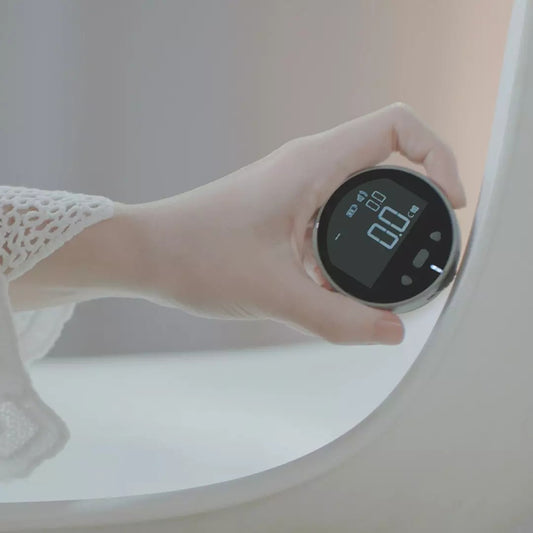 Hand holding a digital device in front of a mirror