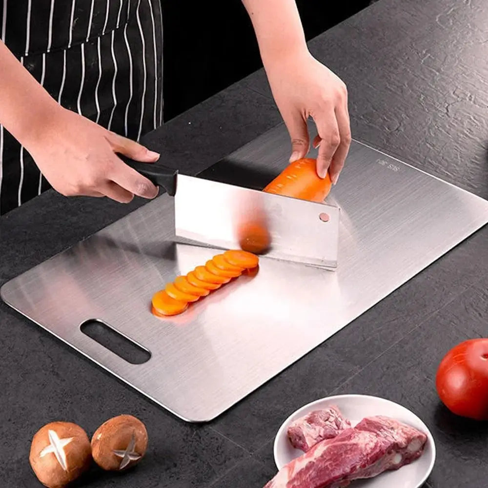 Person slicing vegetables on a large metal cutting board with a knife.