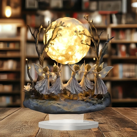 Decorative lamp with fairies and a moon-like light source on a wooden surface.