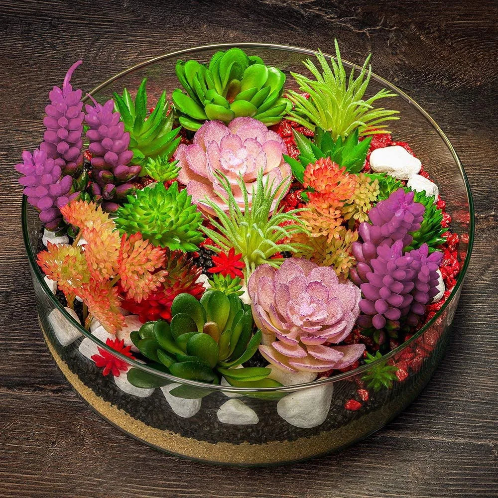 Colorful artificial succulent arrangement in a glass bowl on a wooden surface