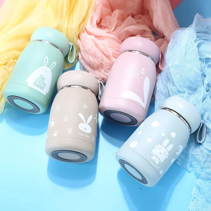 Four colorful thermos bottles with bunny designs on a blue background
