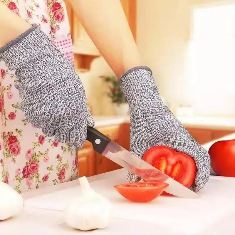 Person wearing cut-resistant gloves cutting tomatoes with a knife on a kitchen counter.