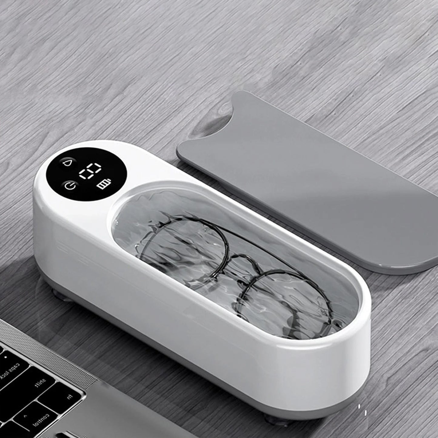 White ultrasonic device with a digital display and glasses inside, on a wooden surface.