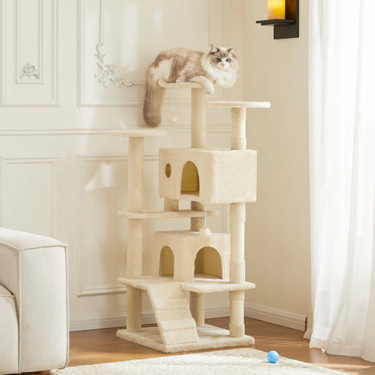 Cat sitting on a multi-level cat tree in a room with a white couch and light-colored walls.