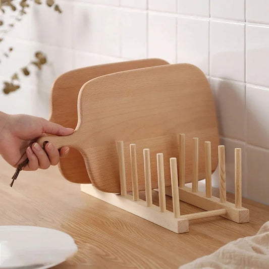 Wooden dish rack with a hand holding a wooden paddle on a kitchen counter.