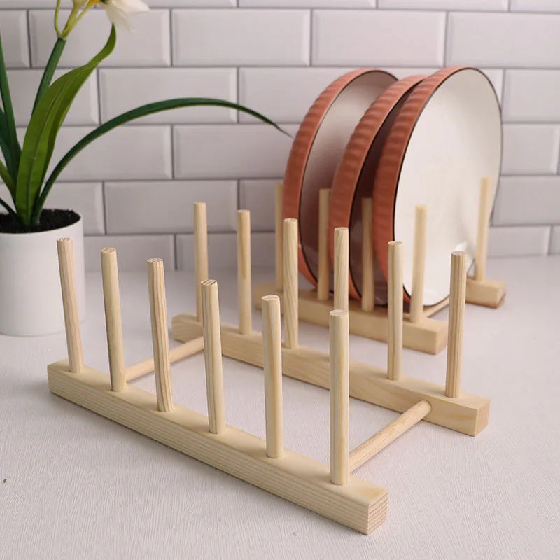 Wooden plate rack with plates on a light surface, plant in the background