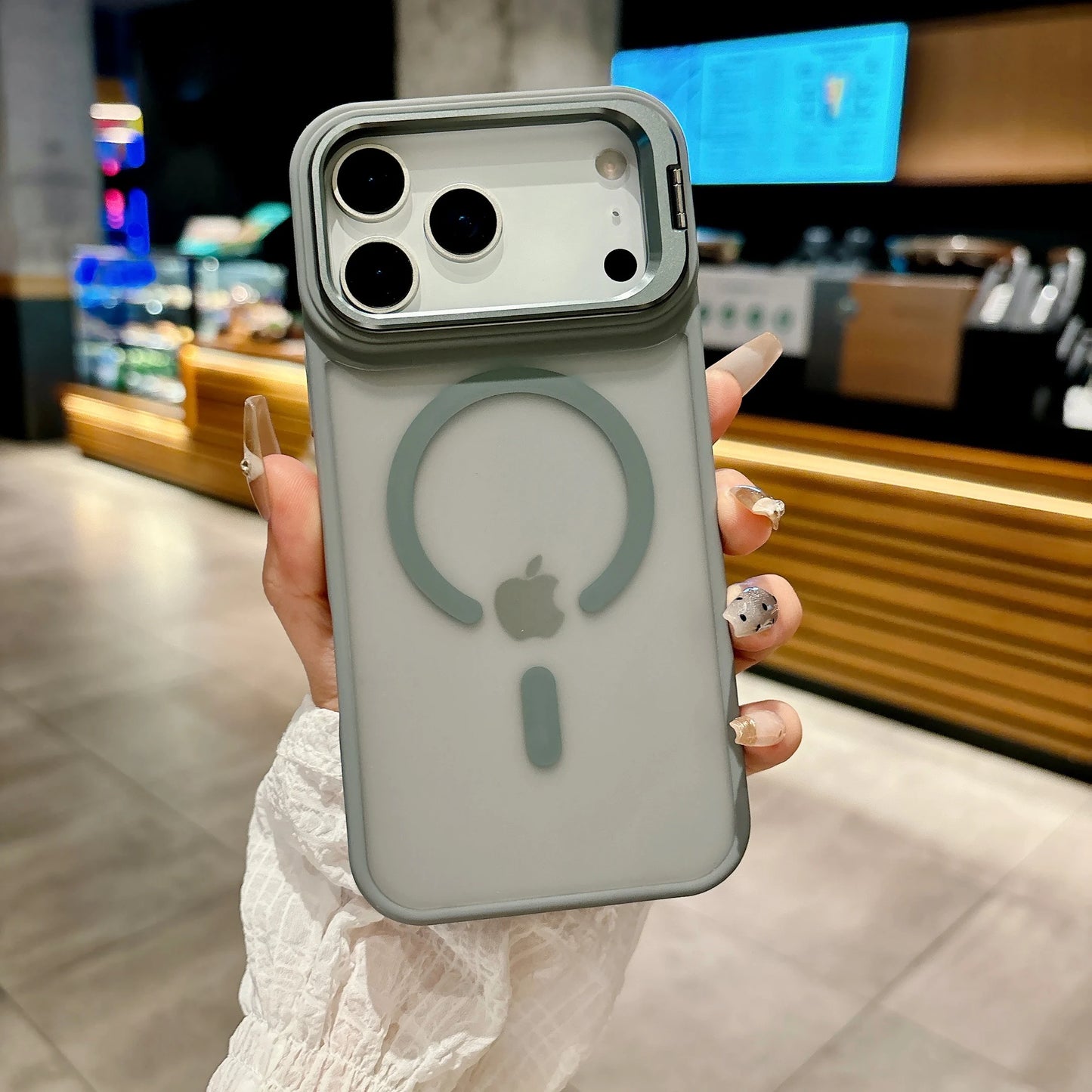 Person holding a phone with a clear case featuring Apple's logo in an indoor setting.