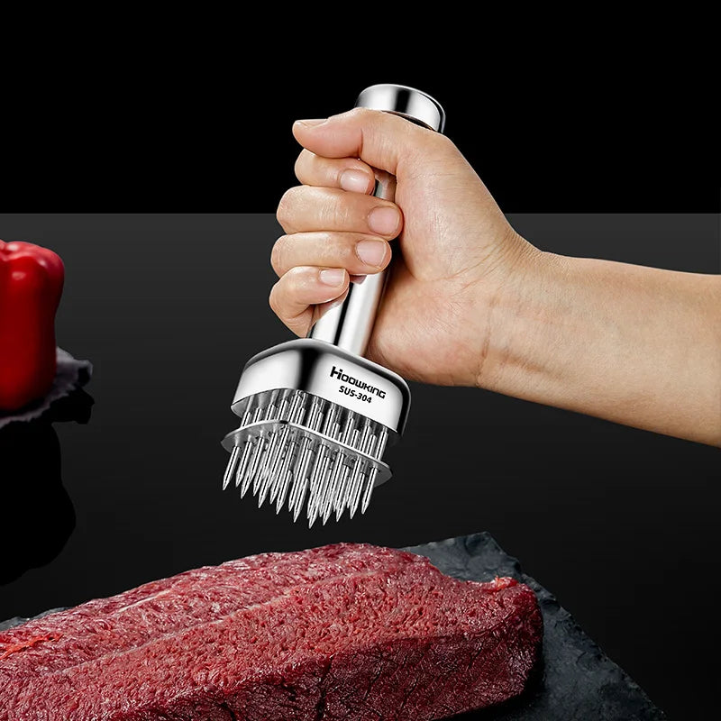 Hand holding a meat tenderizer over a piece of raw meat on a dark surface.