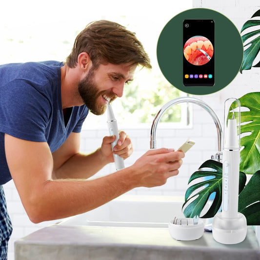 Man using a smart toothbrush with a smartphone app displayed, in a kitchen setting.