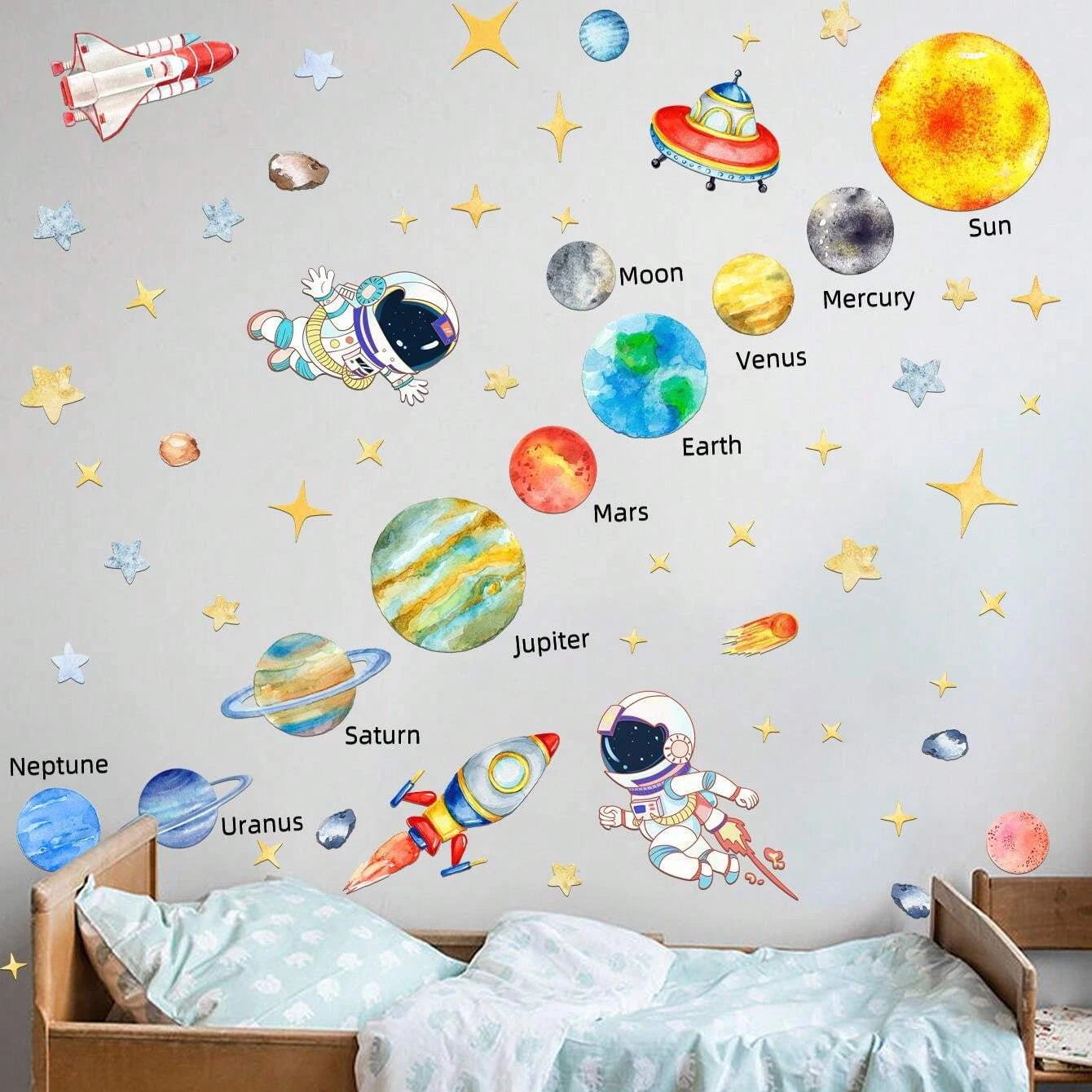 Wall decors of space-themed planets, stars, and astronauts on a wall above a bed.
