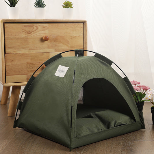 Green pet tent on a wooden floor with a wooden dresser and plants in the background