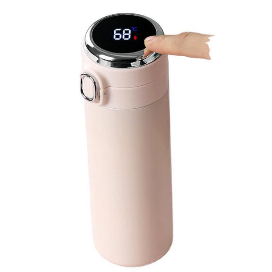 Digital temperature display on a pink thermos bottle with a hand interacting with it.