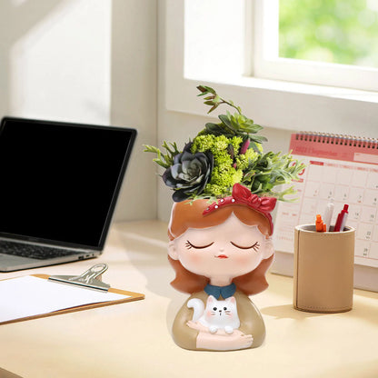 Decorative planter shaped like a girl with a cat on a desk with a laptop and calendar.