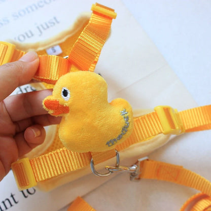 Yellow duck-shaped dog harness held by a hand on a white background