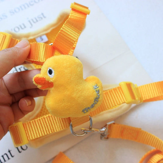 Yellow duck-shaped dog harness held by a hand on a white background