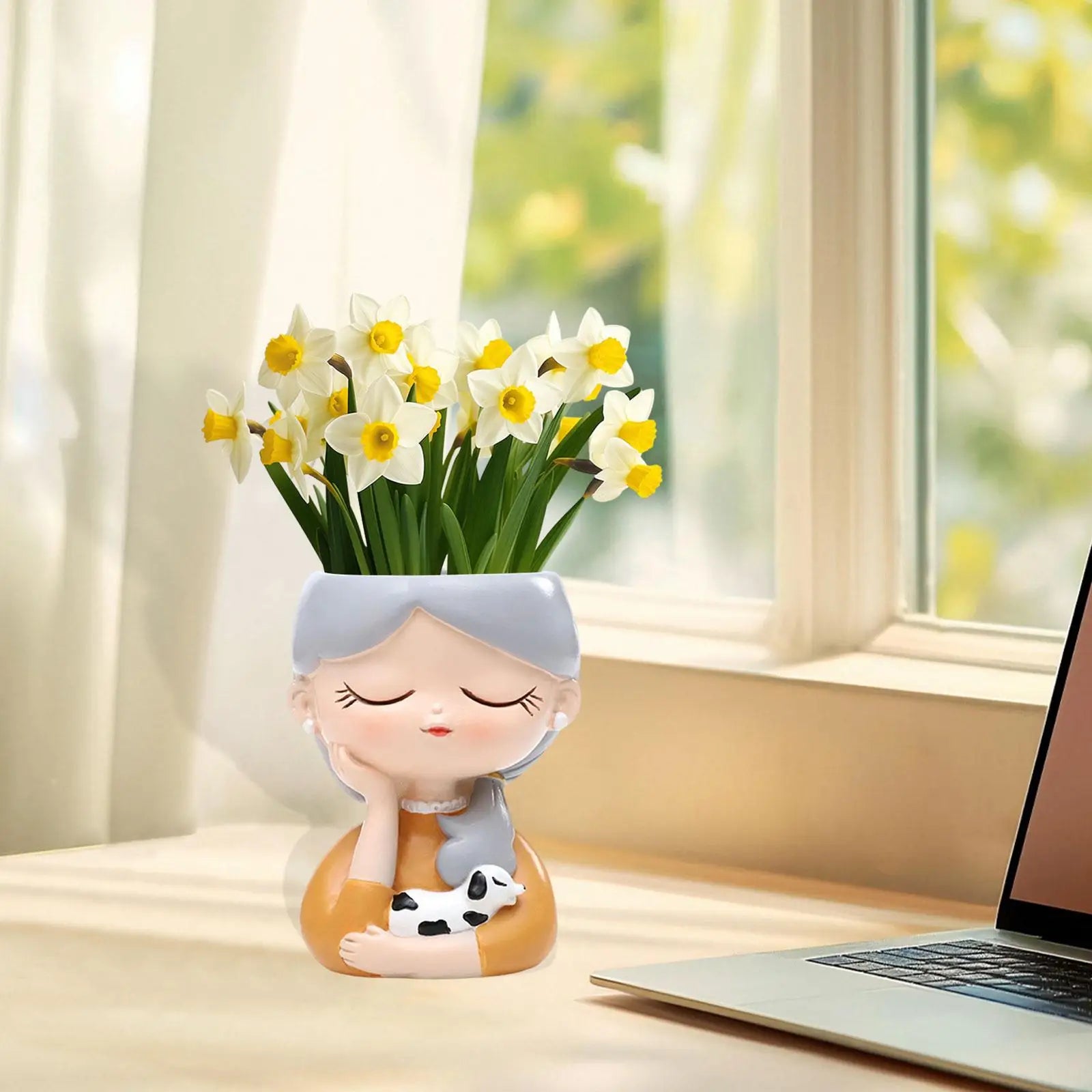 Decorative vase shaped like a girl with flowers on a desk next to a laptop.