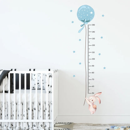 Children's room with a crib, growth chart with a blue balloon and pink bunny, and star decorations.