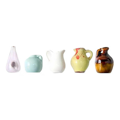 Set of five ceramic pitchers in various colors on a white background