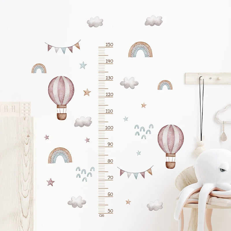 Children's room with wall decals including hot air balloons, rainbows, and a growth chart.