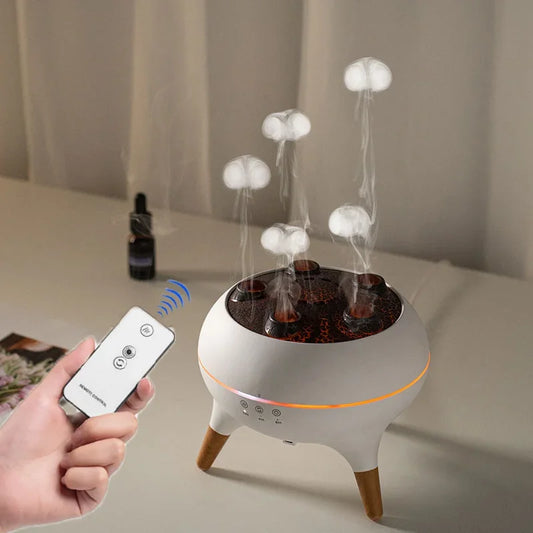 White electronic diffuser with mushroom-shaped lights on a table, held by a hand with a remote control.