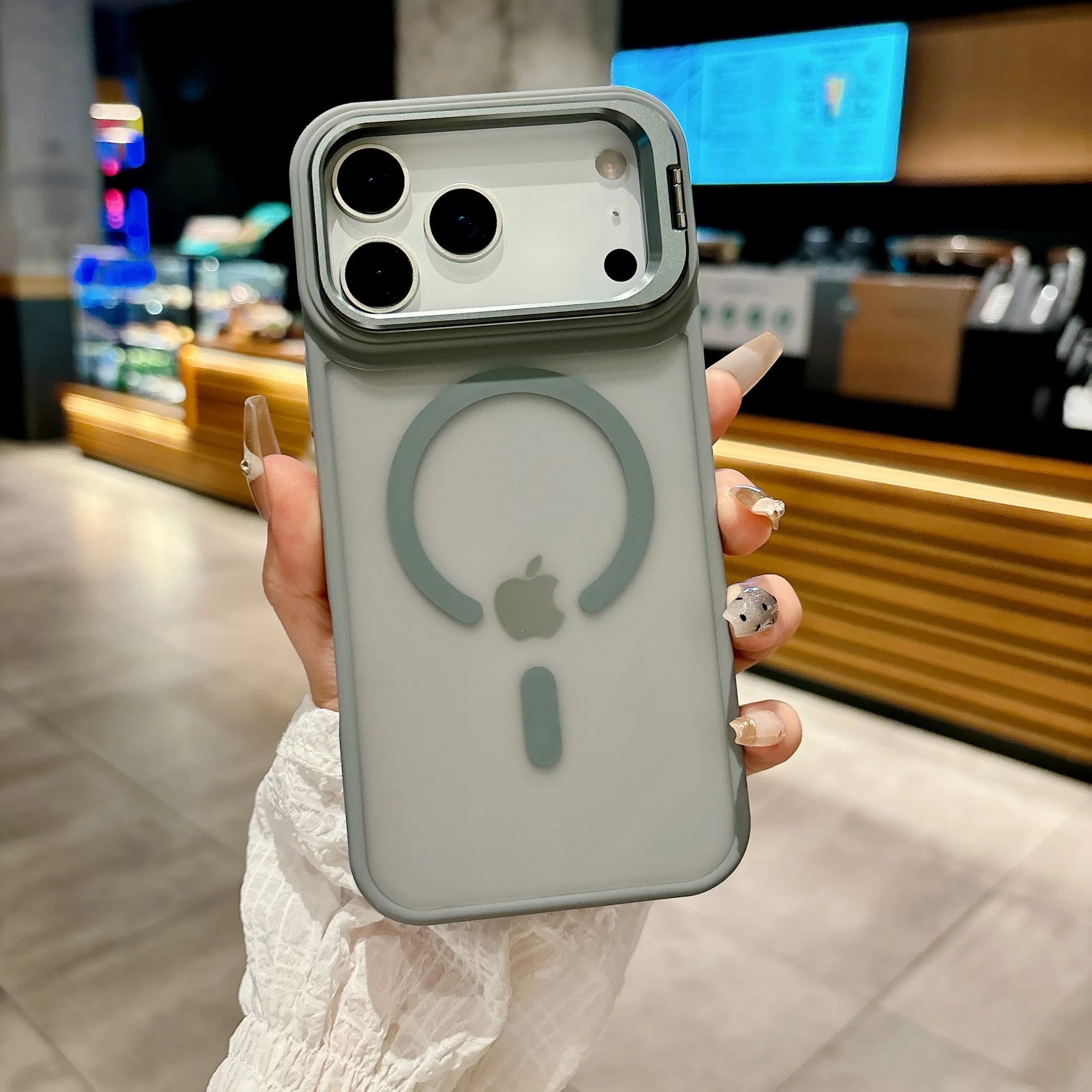 Person holding a phone with a clear case featuring Apple's logo in an indoor setting.