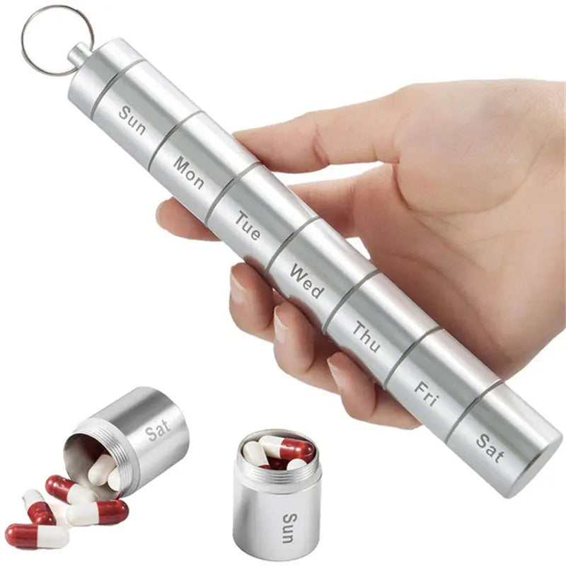 Silver pill organizer with compartments labeled for each day of the week, held by a hand.